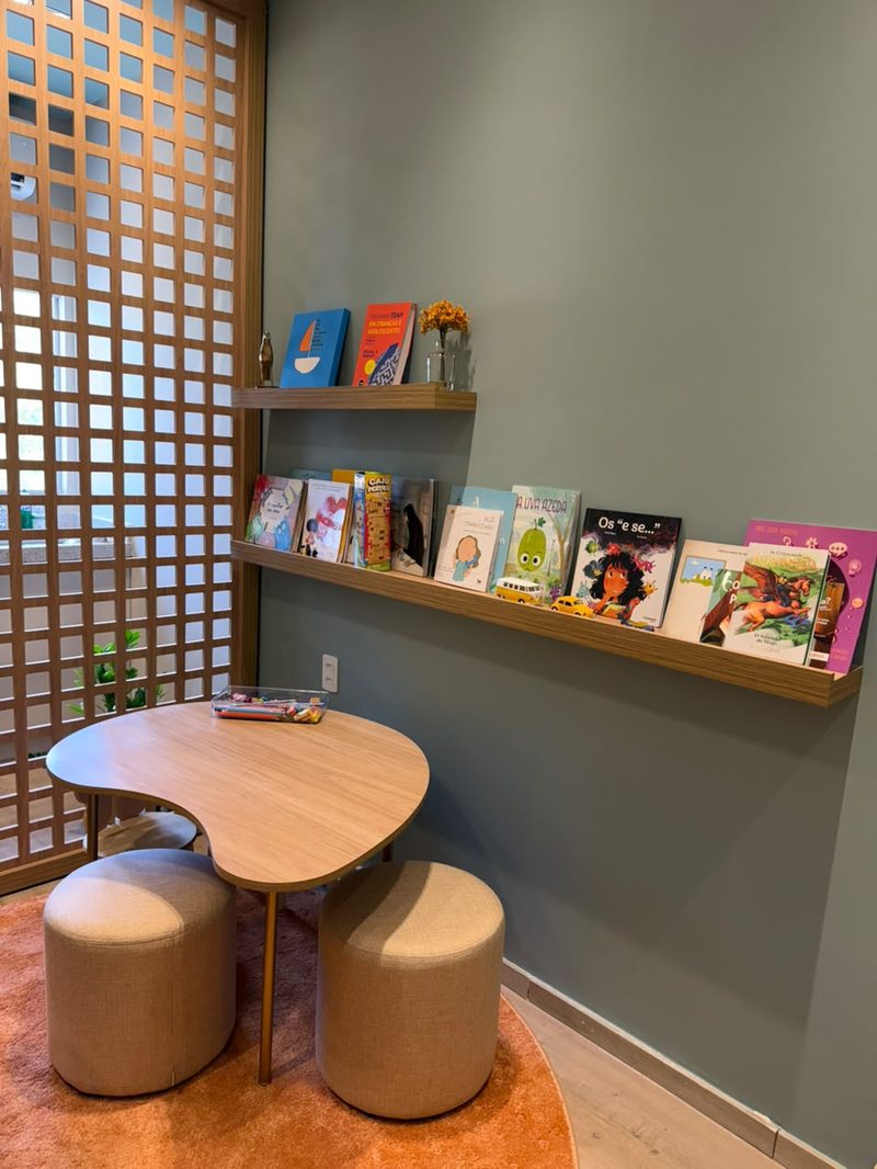 Cantinho infantil com mesa, puffs e livros em prateleira