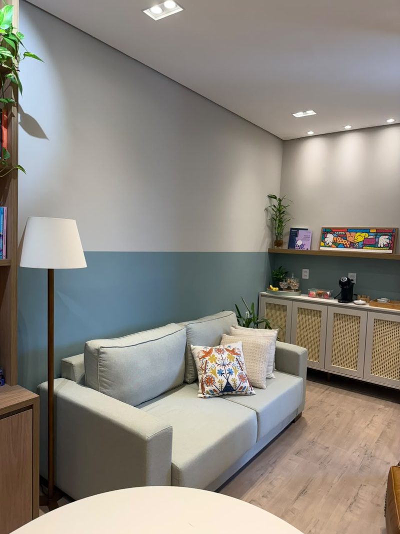 Sala de atendimento com sofá, abajur e prateleira com plantas
