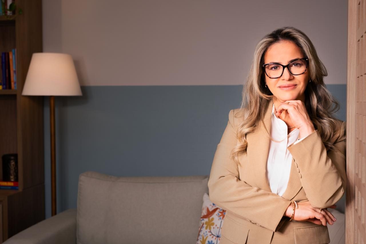 Renata Chmieleski sentada no consultório, apoiando o rosto na mão